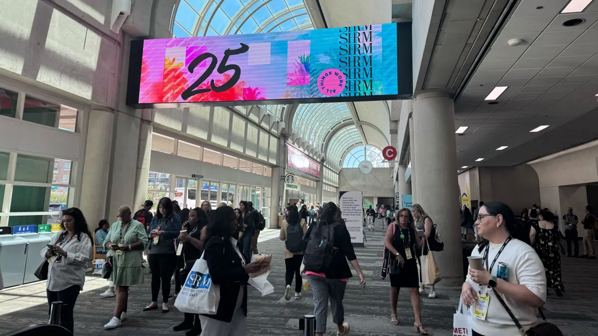 SHRM25 attendees walk under signage for the conference.