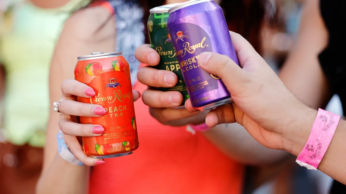 A photo of hands holding canned cocktails.