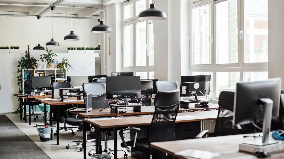 Interior of modern office with empty chairs and PCs on desks.