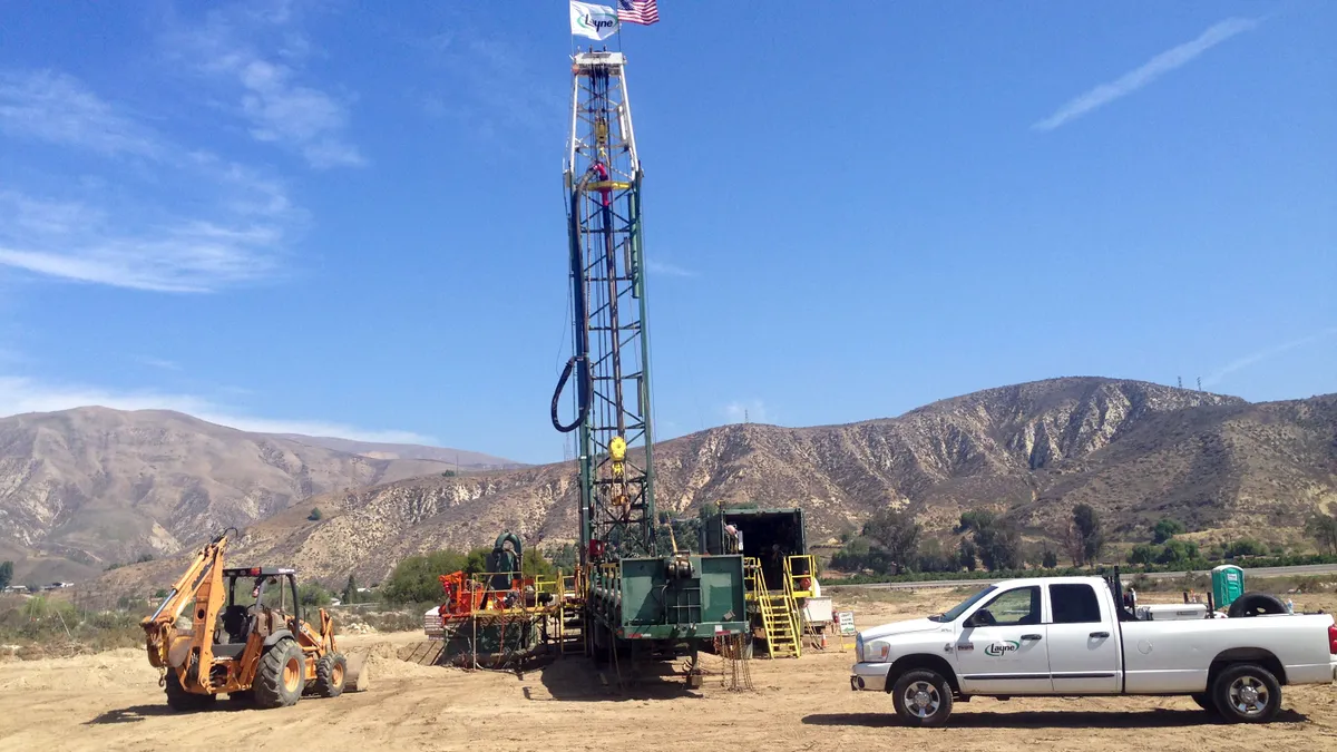 A construction crew drills a water well.