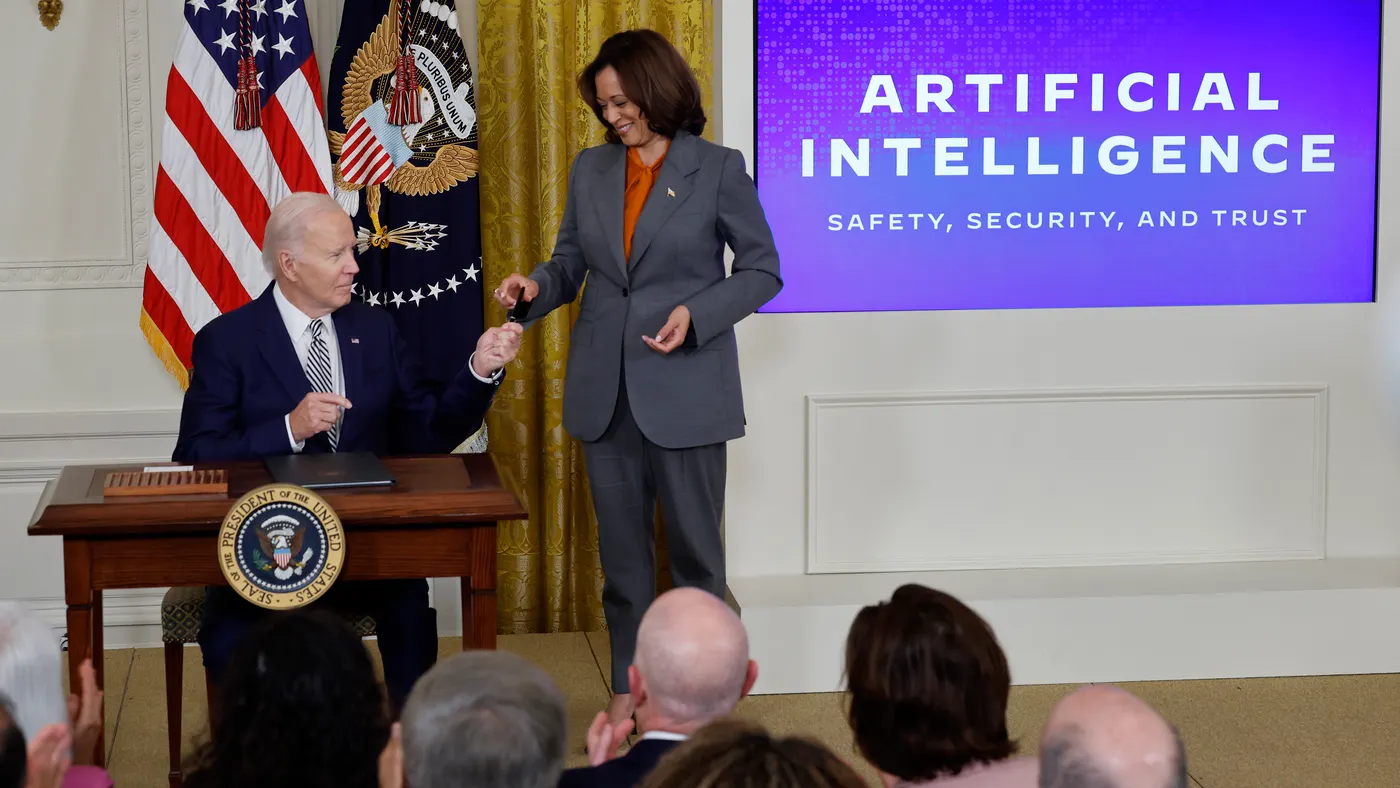 President Joe Biden hands Vice President Kamala Harris a pen used to sign an executive order at the White House.