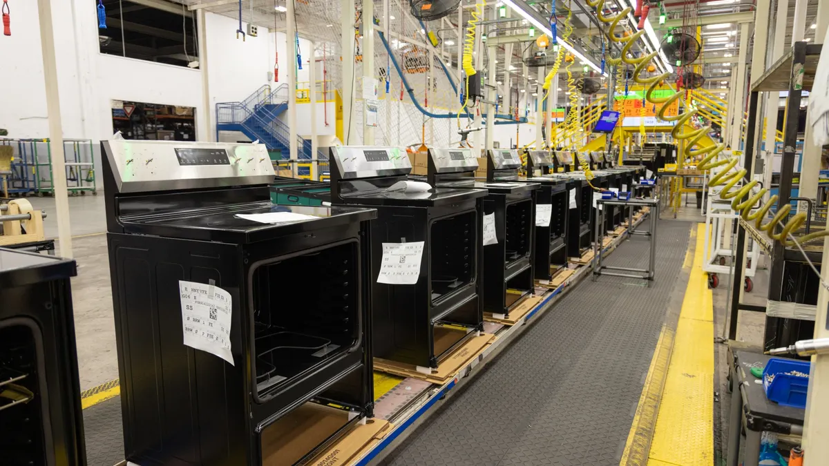 A row of black ovens without doors in a factory.