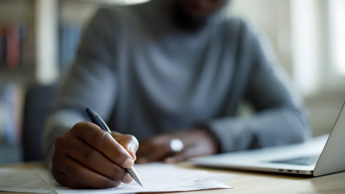 A person writes with a pen.