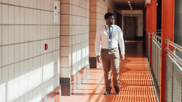 A teacher looks to the side while walking down a school hallway.