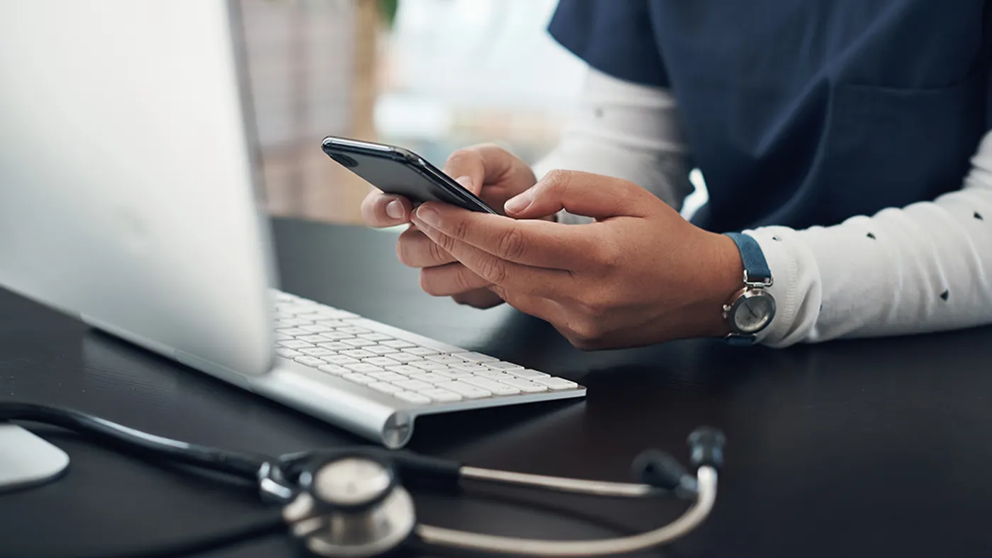 Shot of an unrecognizable doctor using a cellphone in an office