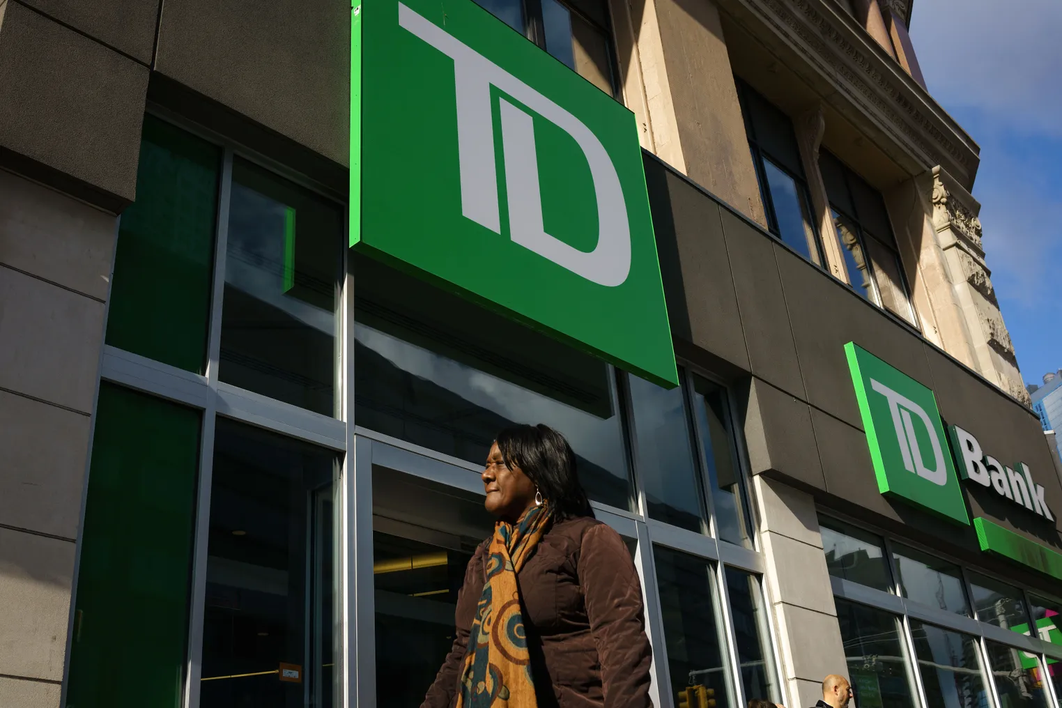 Woman stands under TD Bank sign.