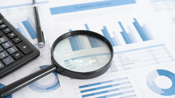 Magnifying glass with business report on financial advisor desk.