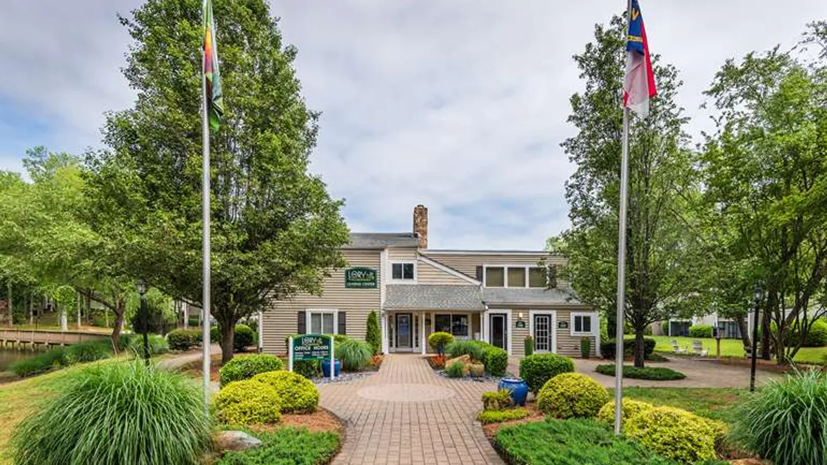 Apartment entrance with trees and flags in the foreground.