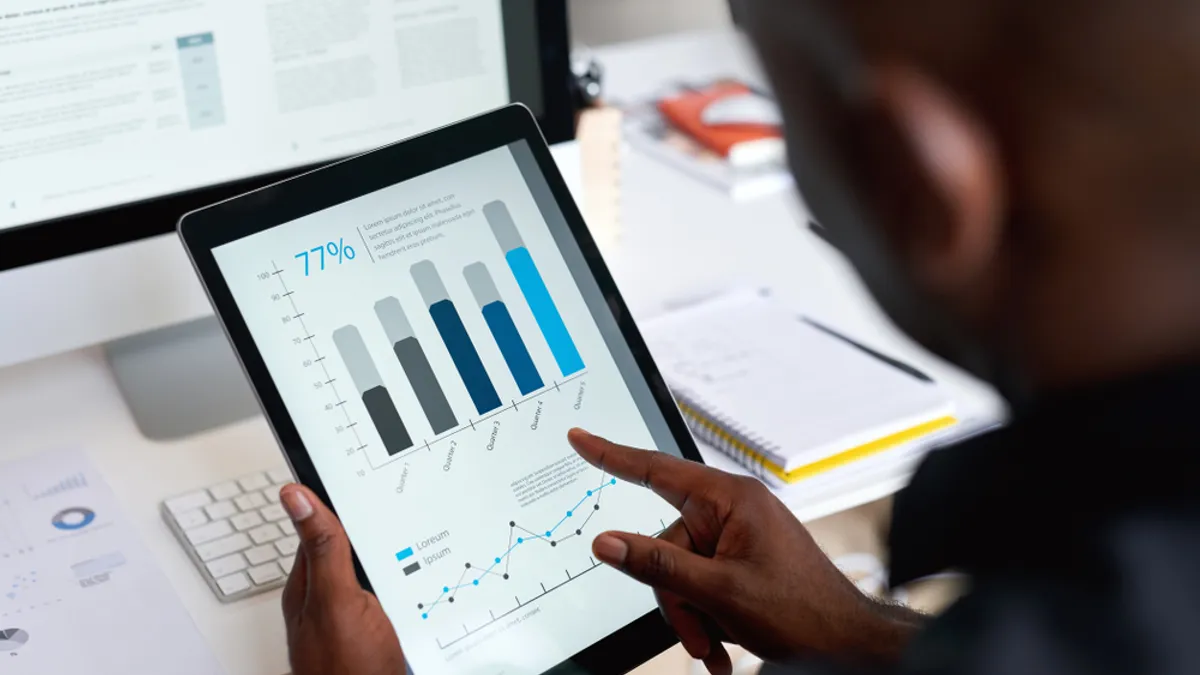 Businessman using digital tablet computer with financial data on screen in office