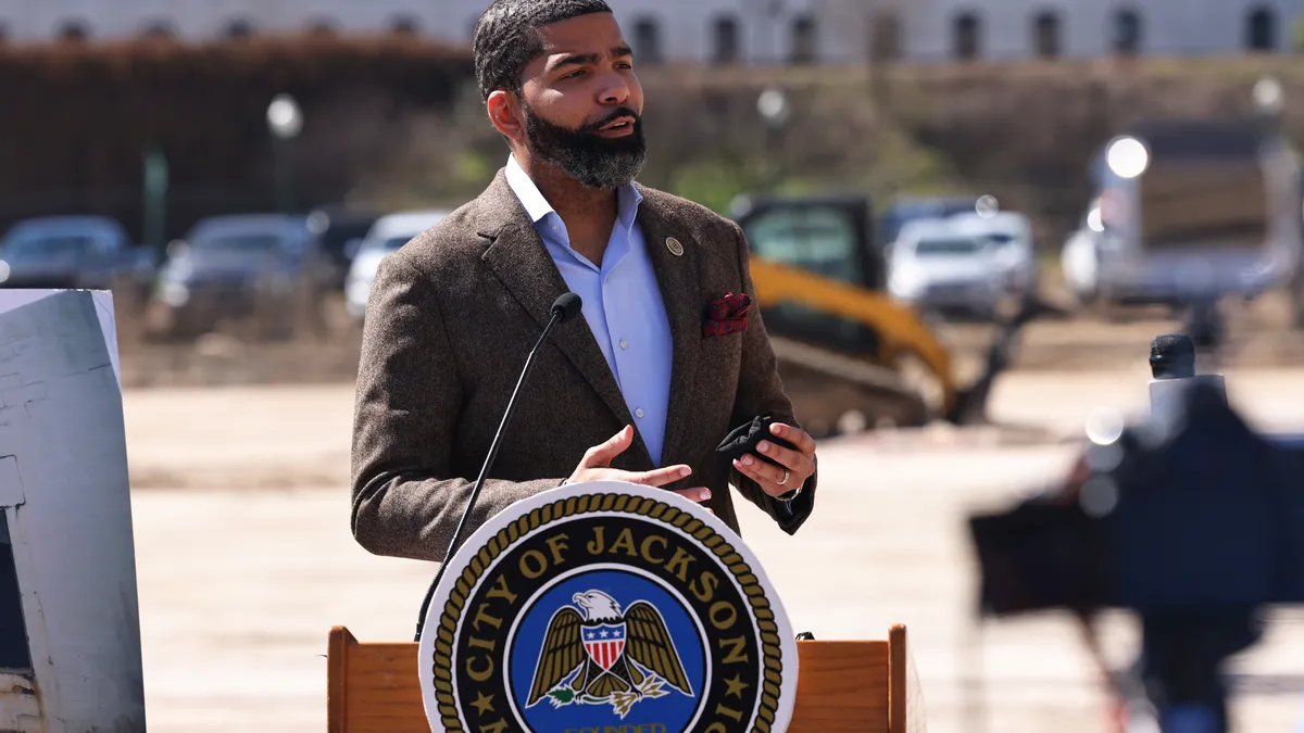 Man in suit jacket speaking at a podium during press conference