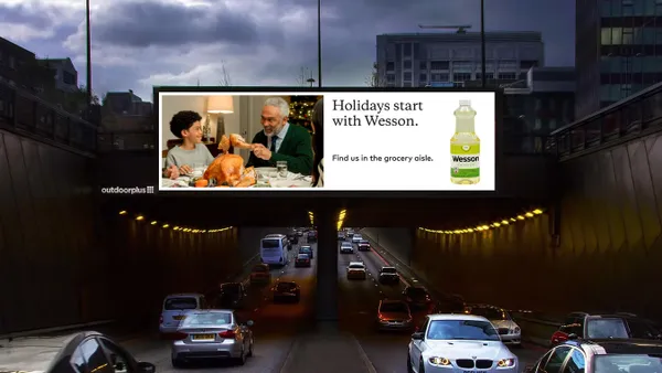 A billboard for Wesson Oil sits in the dark above a road.