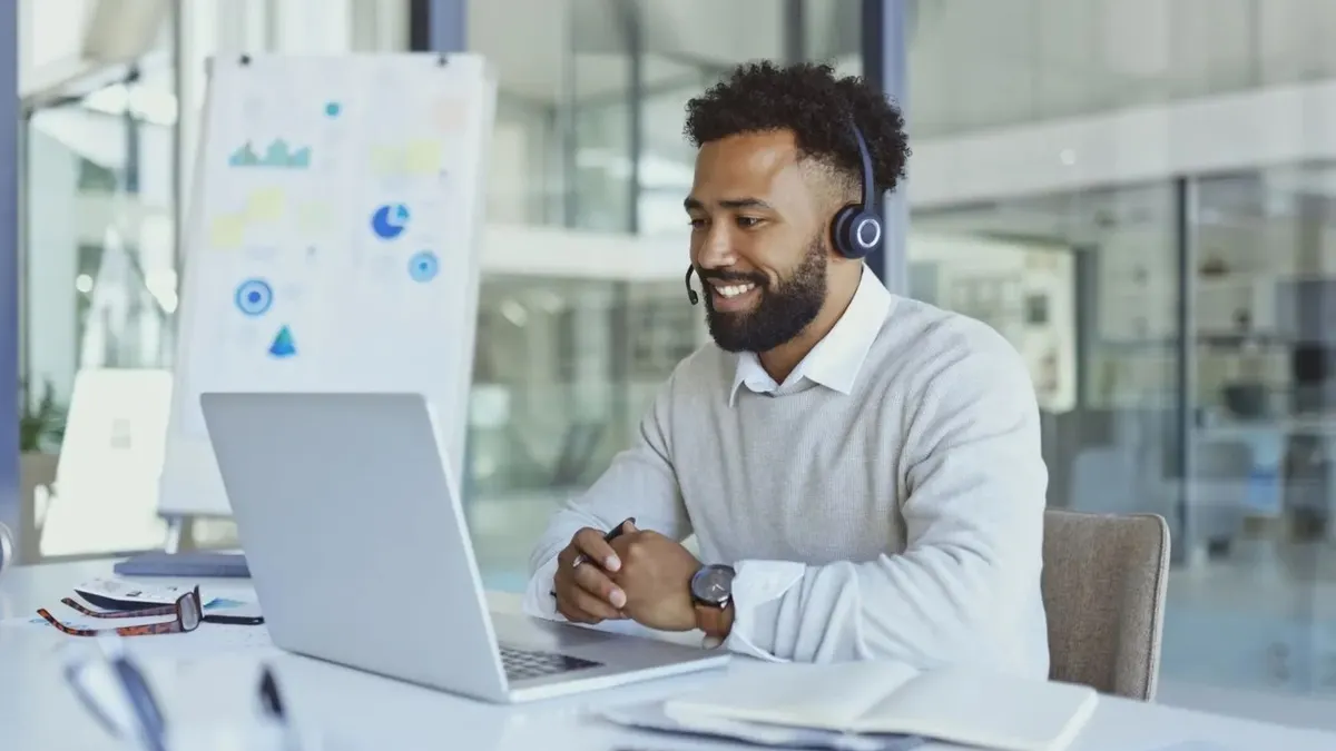 A man in a office with a headset on a conference call