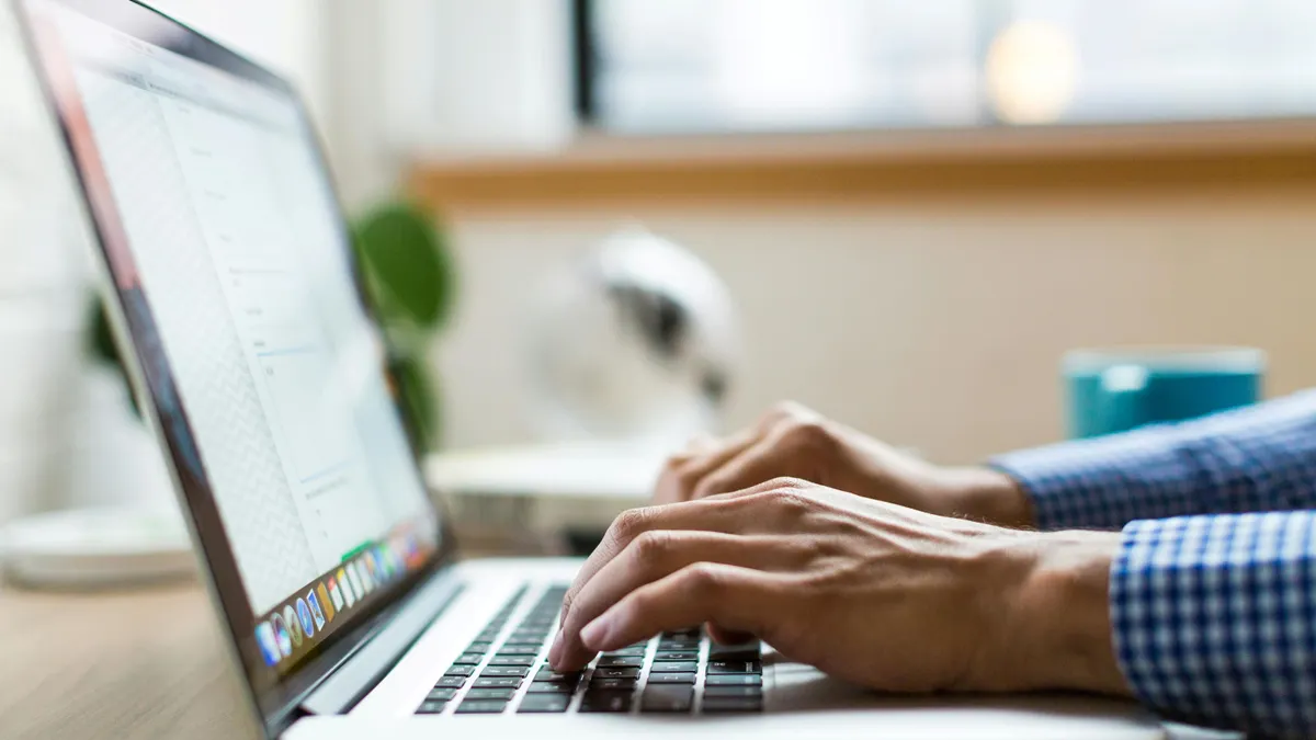 Close-up of hands typing on a laptop computer.