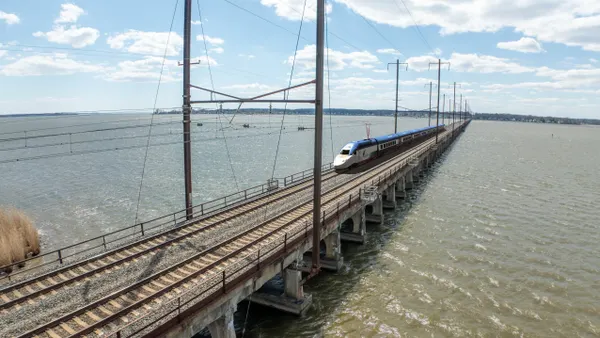 An elevated view shows a train crossing a bridge over a river.