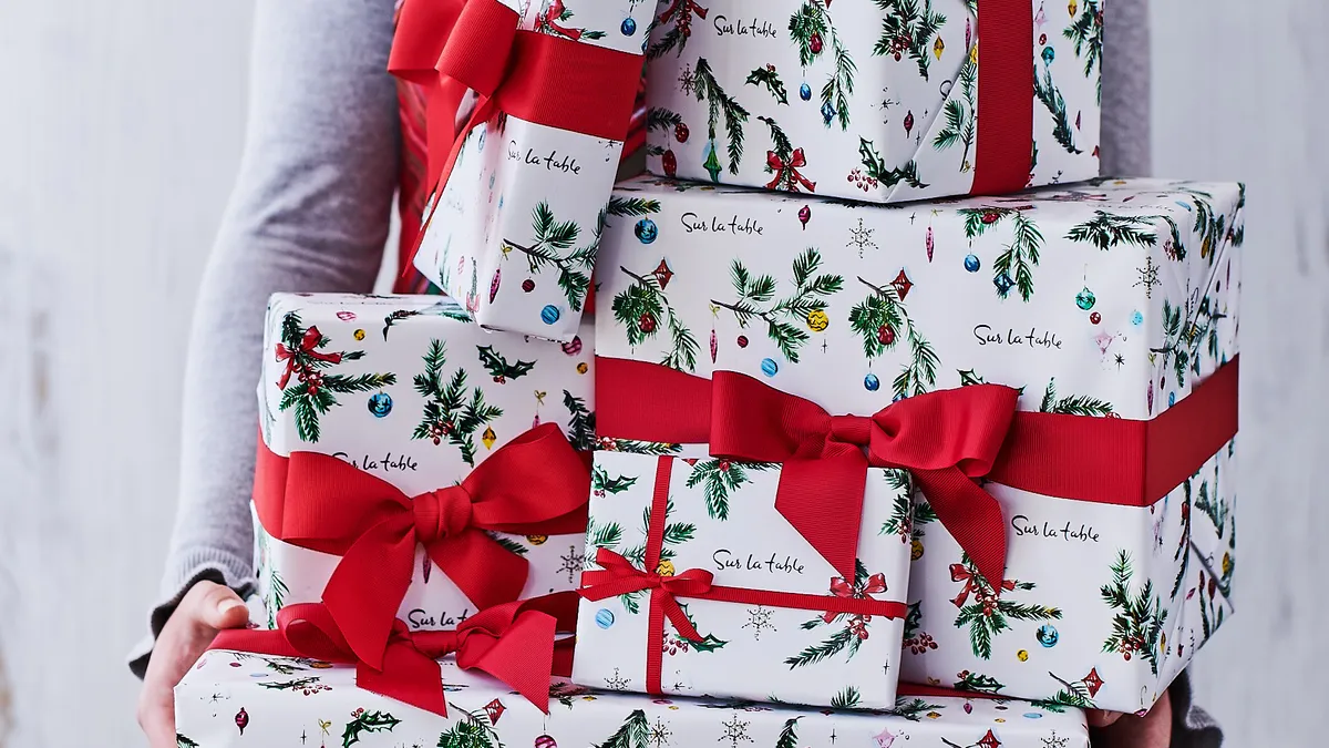 A person holding wrapped gifts from Sur La Table.