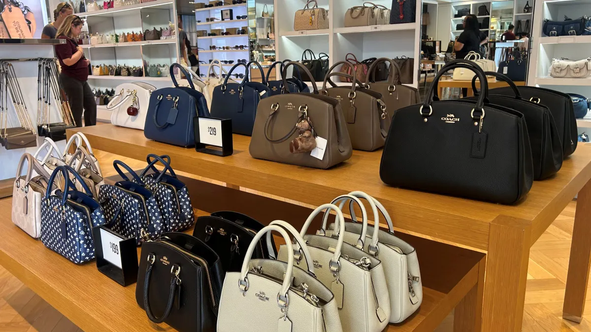 Handbags are on a table for sale in a Coach store