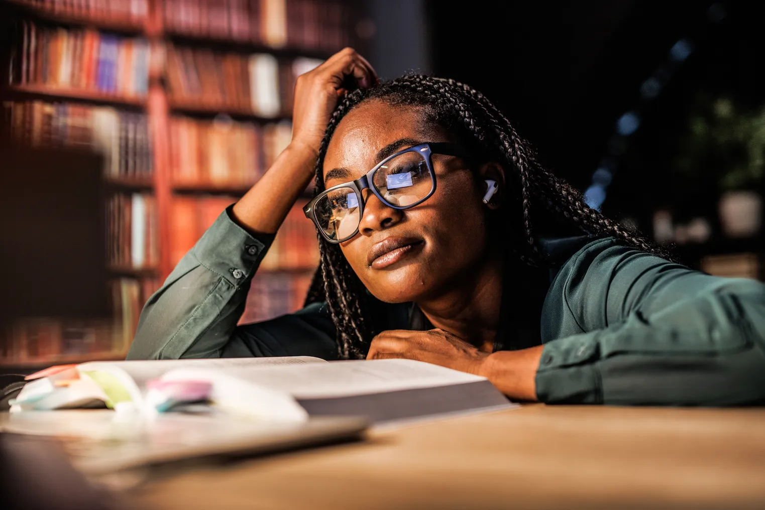 A young college student looks at a textbook in a library.