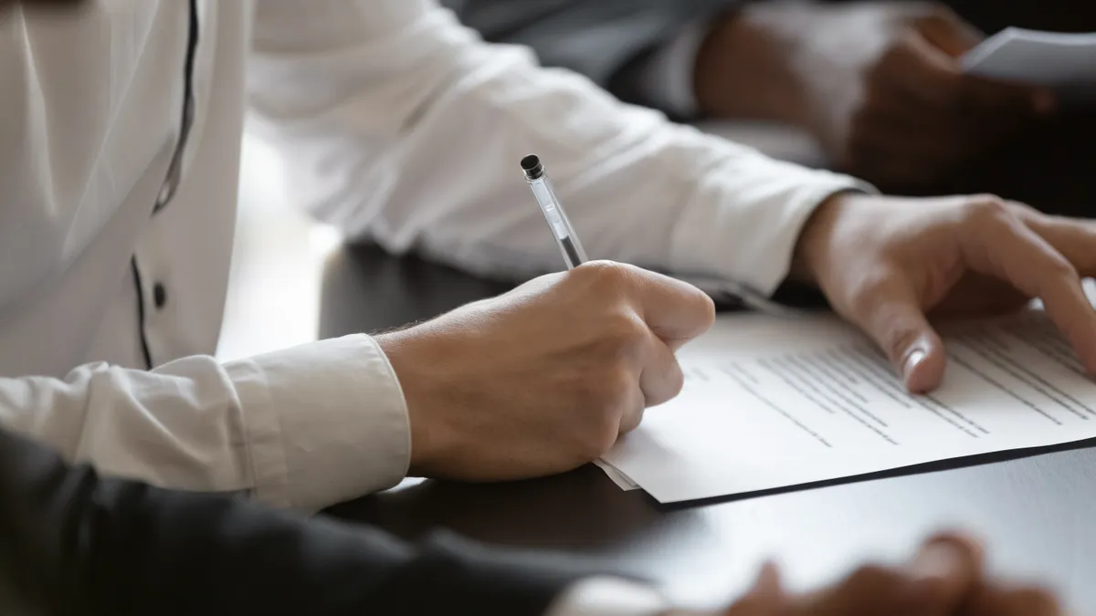 A hand writes on a piece of paper.