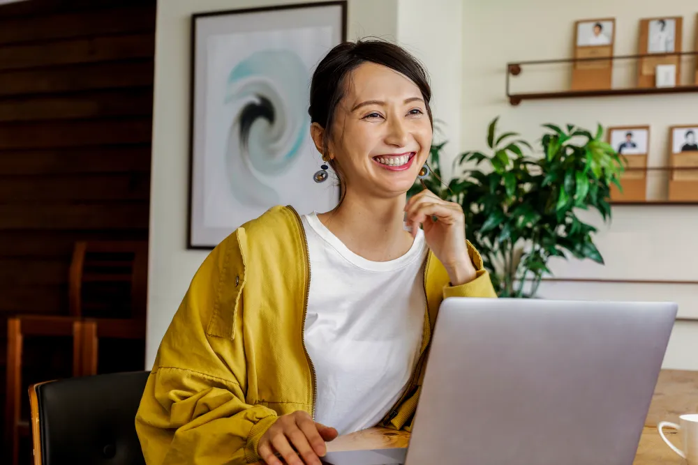 Woman smiling while working on a laptop.