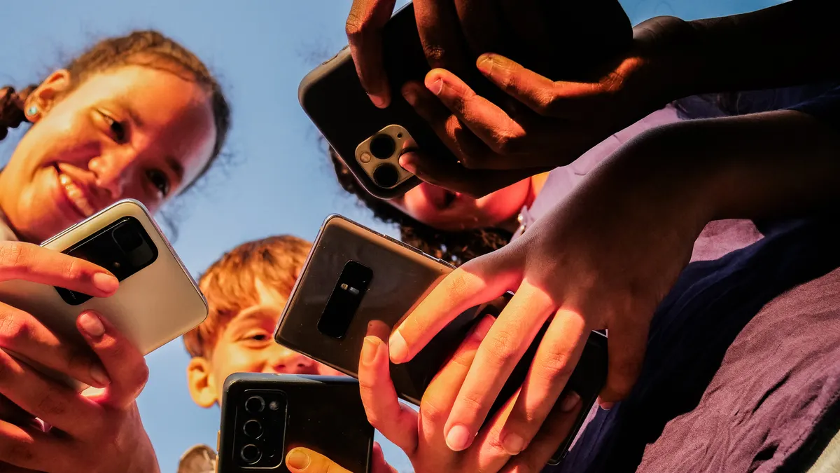 Close-up of teenage friends using mobile phone outdoors.