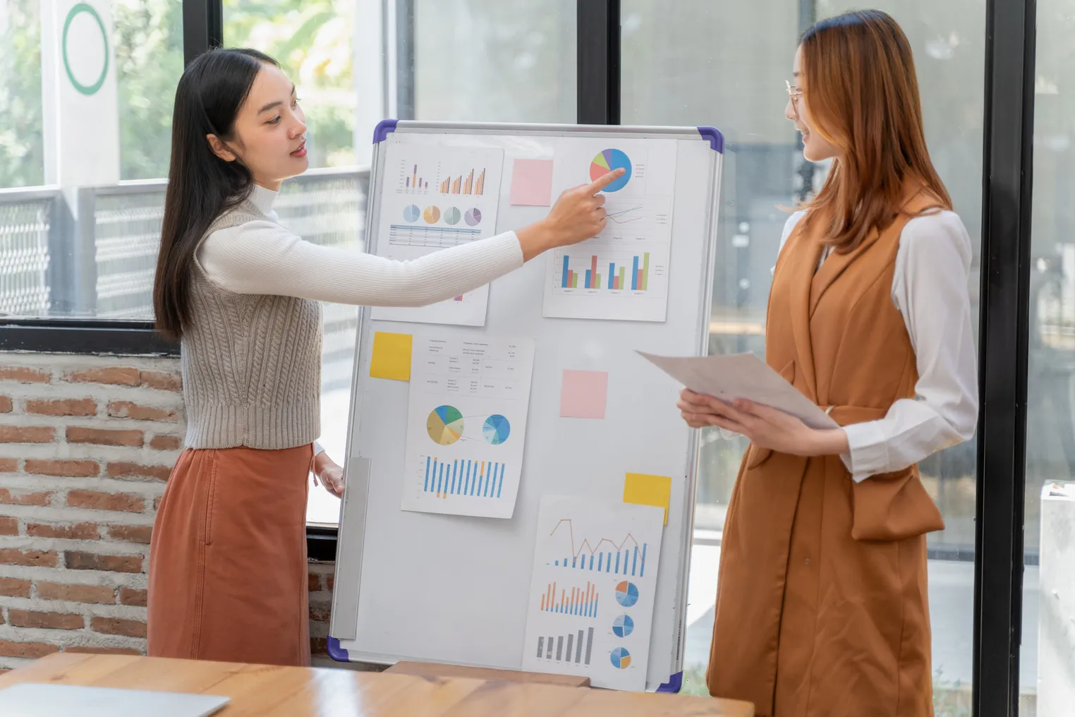 A high school student points to a business presentation while standing next to another classmate.