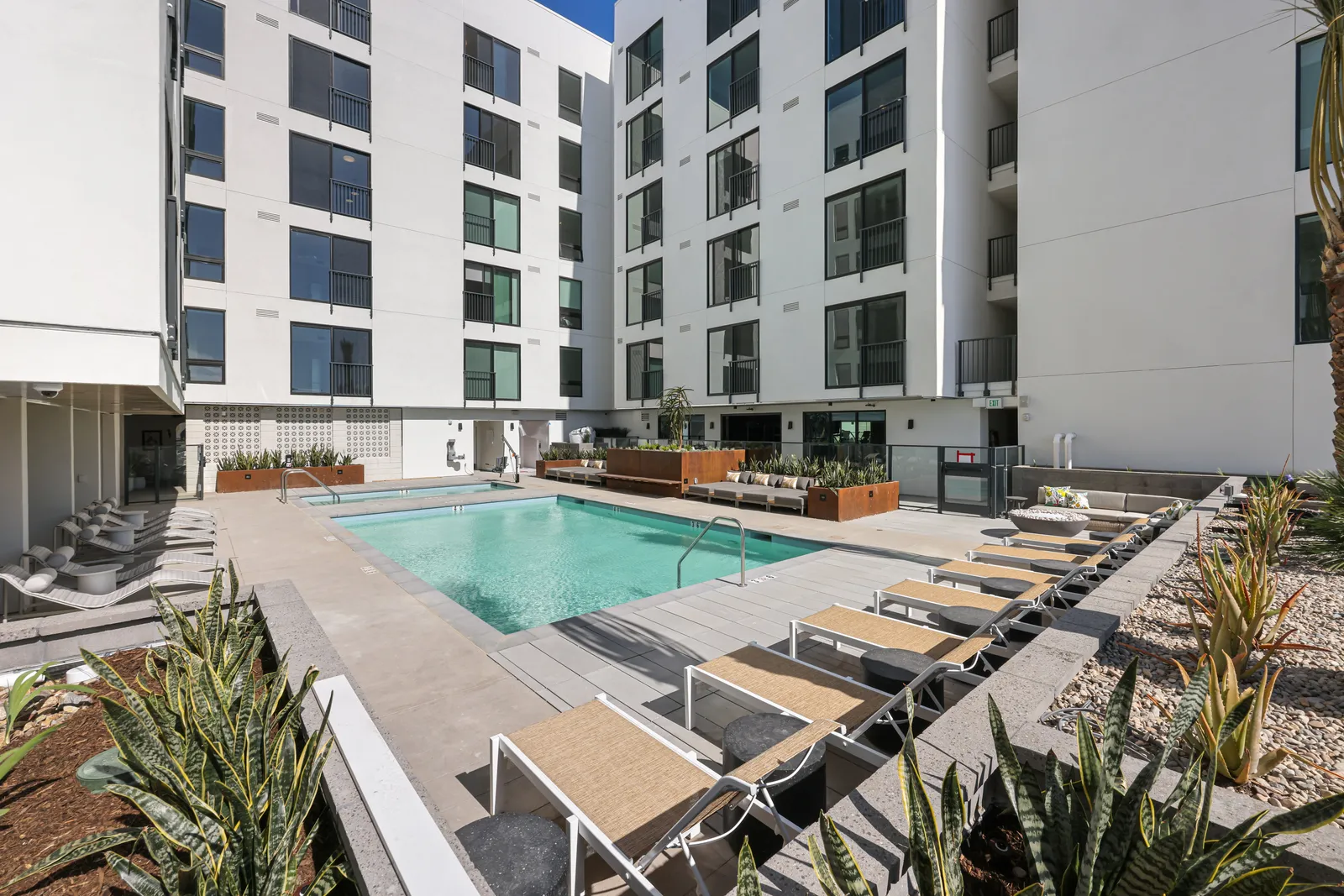 An outdoor pool area surrounded by white walls and windows.