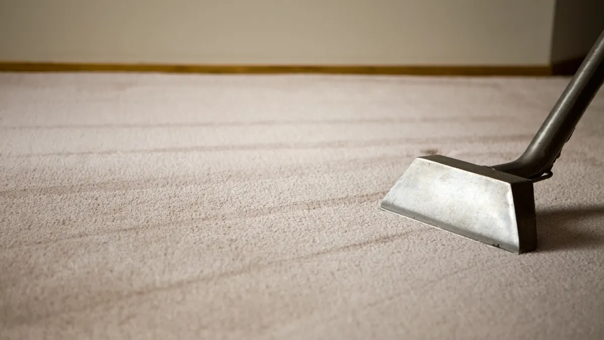 A silver valcuum on a clean, beige carpet.