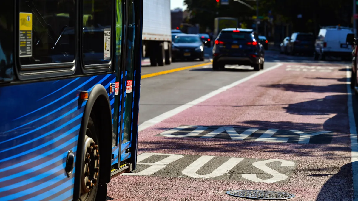 Close-up of blue New York City transit bus along a marked bus lane.