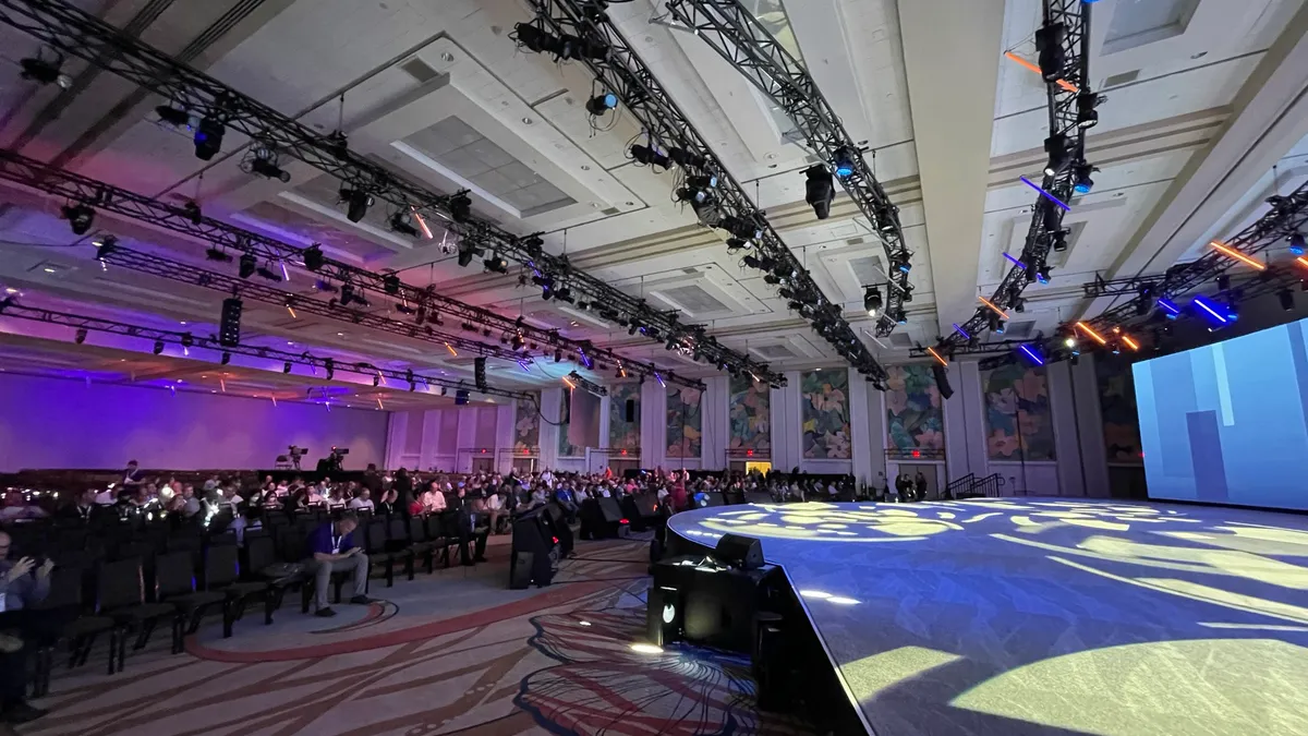 A large conference room with an audience awaiting a presentation.