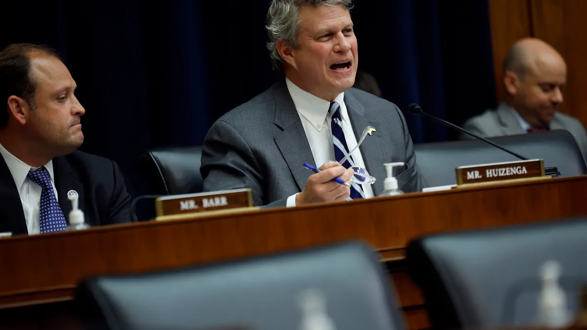 Rep. Bill Huizenga speaks with his glasses in his right hand at a congressional hearing.