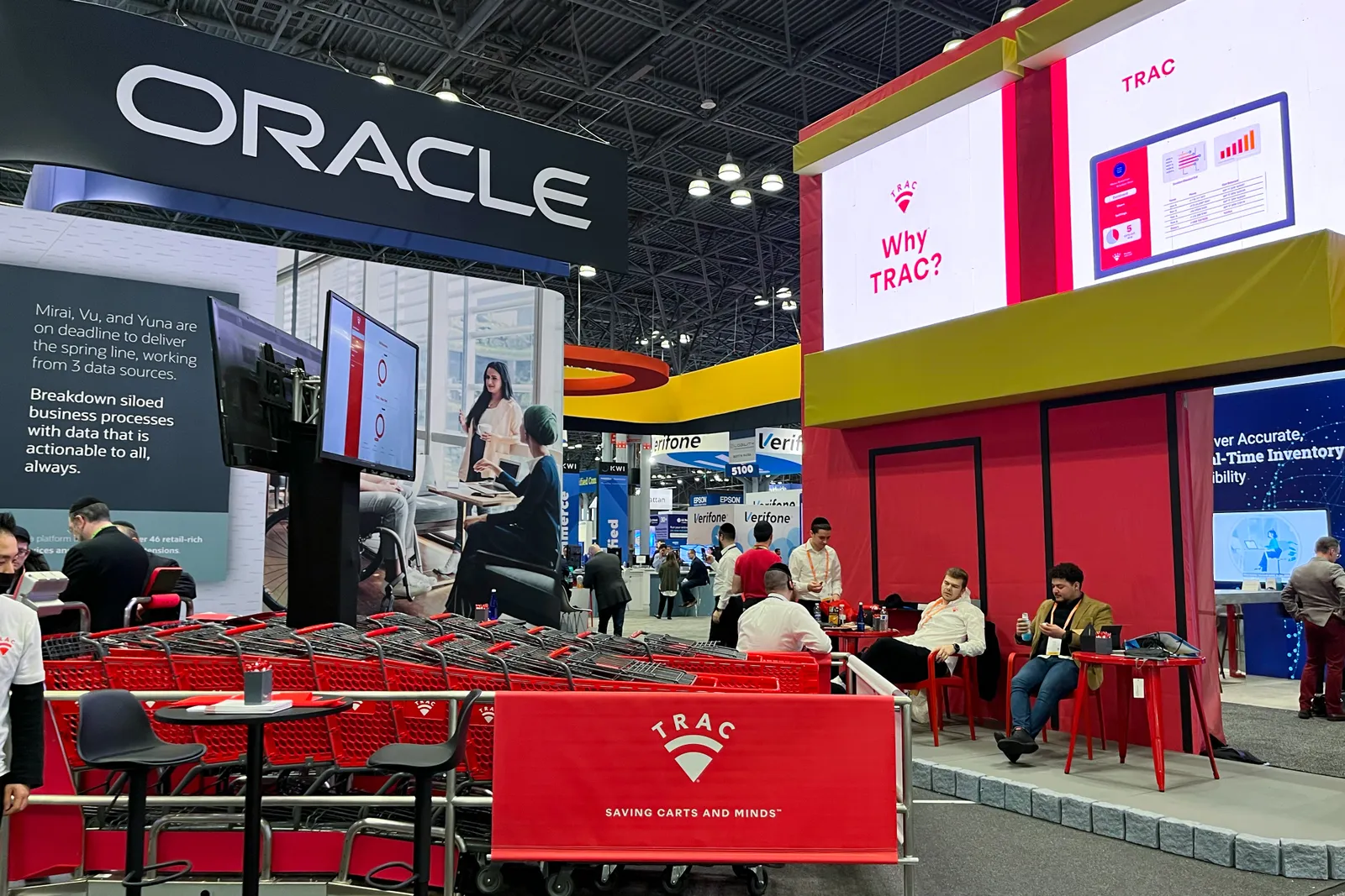 A booth with red shopping carts on an exhibition floor at a conference.