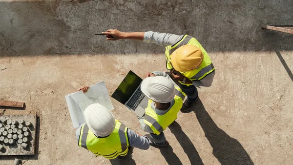 construction workers look at a laptop