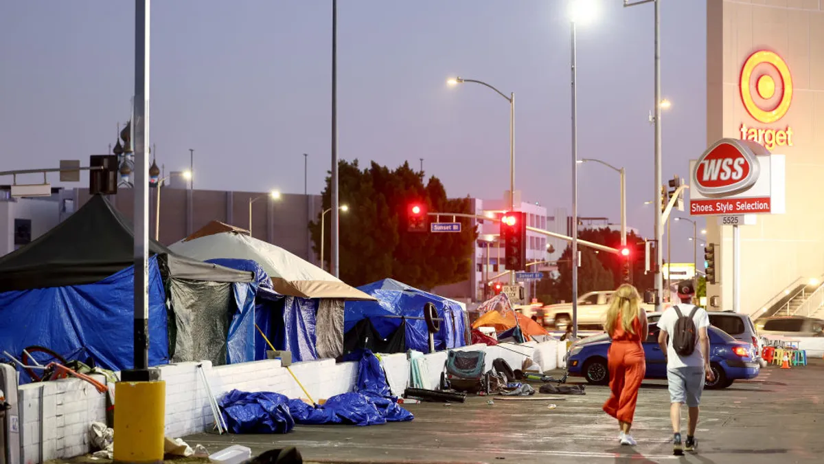 People walk in a lit parking lot at night next to numerous tents.