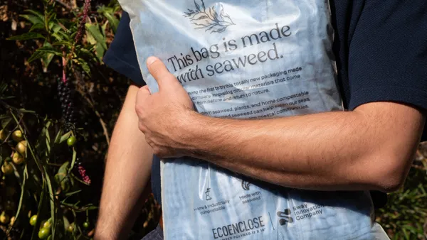 An arm clutches a Sway polybag containing a garment. Writing printed on the bag reads "This bag is made with seaweed."