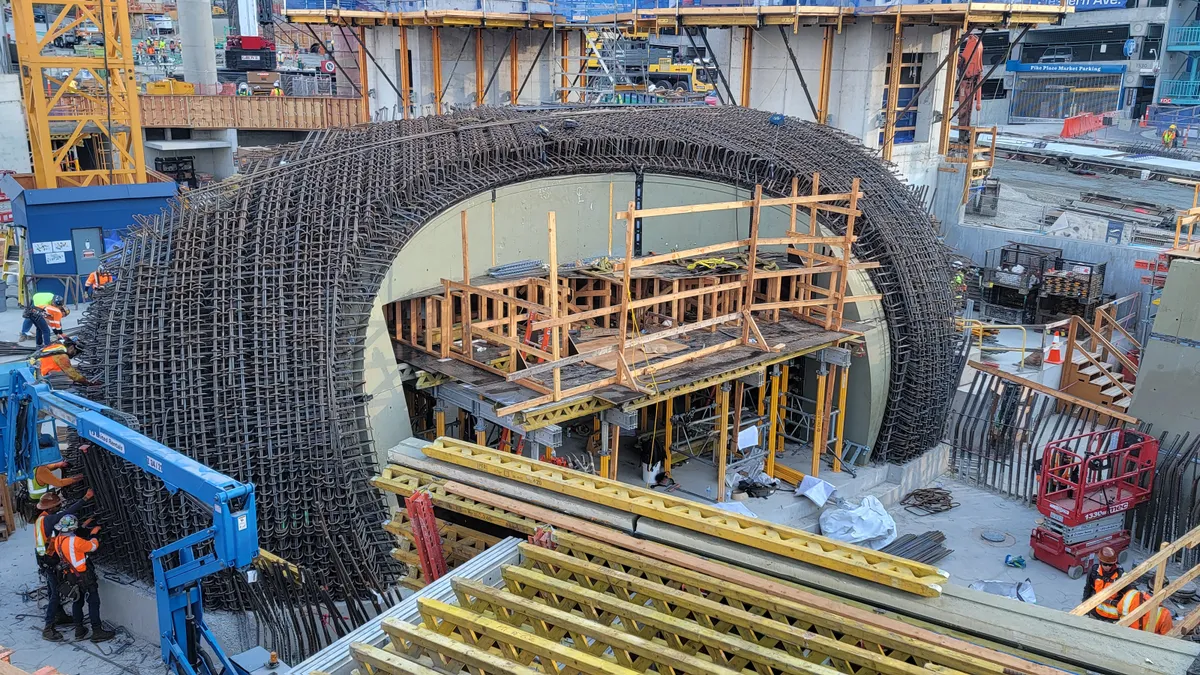 The underlying rebar of a massive curved concrete aquarium tank is visible on a construction jobsite.