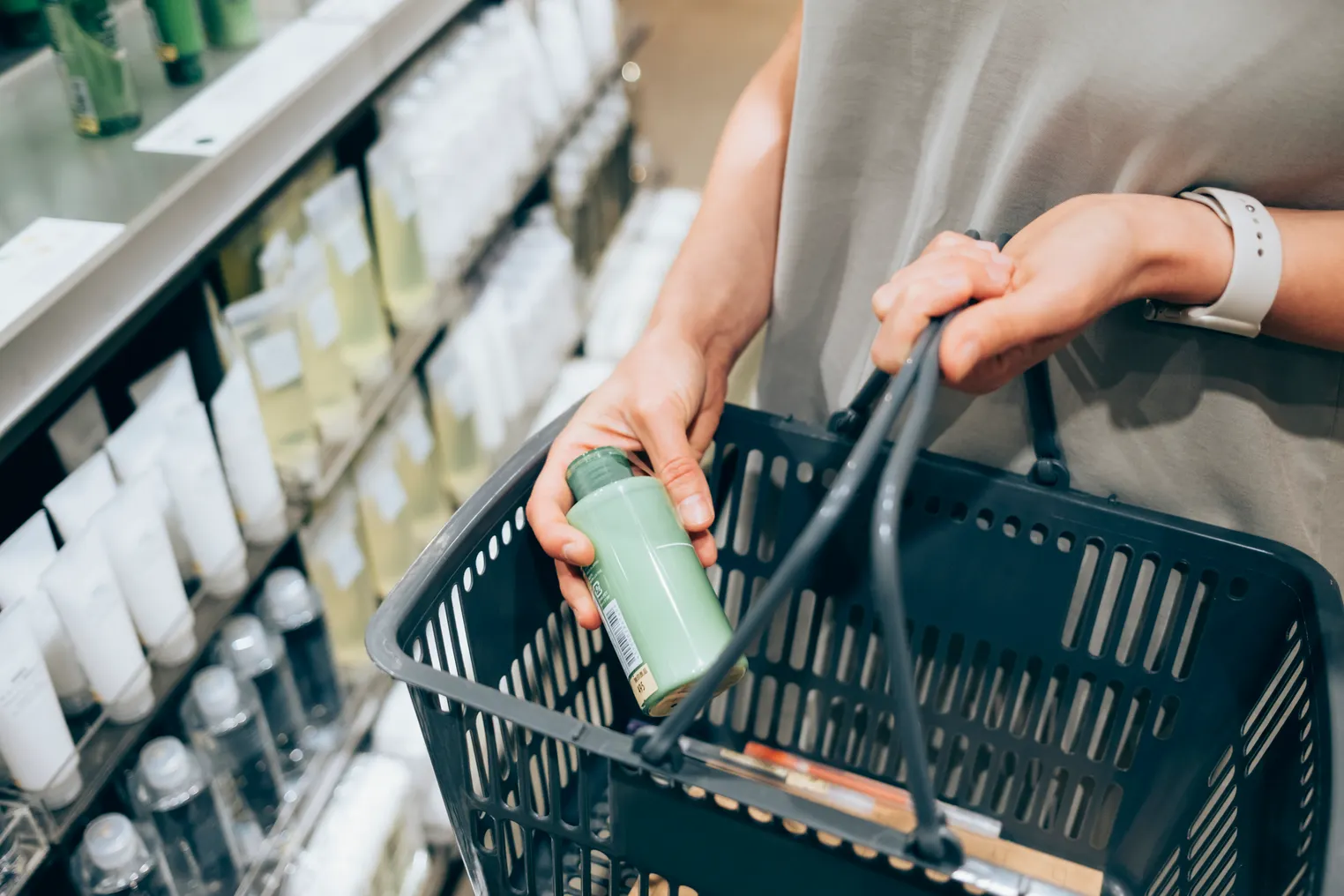A person in a store places a cosmetic product into a shopping basket