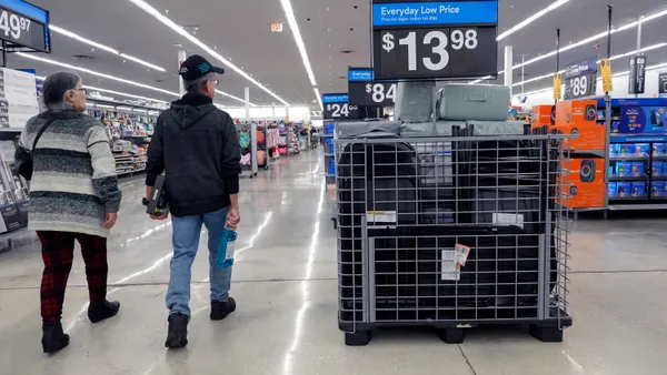 Two people walk down a store aisle past a sign that reads, "Everyday Low Price."