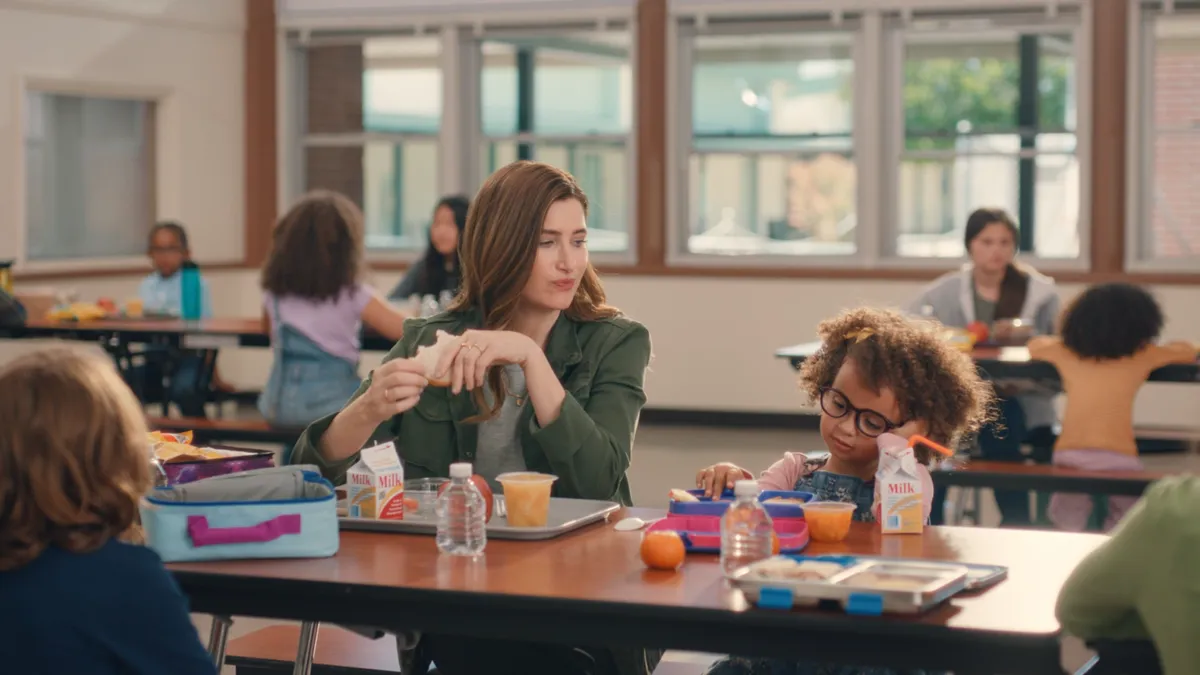 Actress Kathryn Hahn sits in a cafeteria with a student