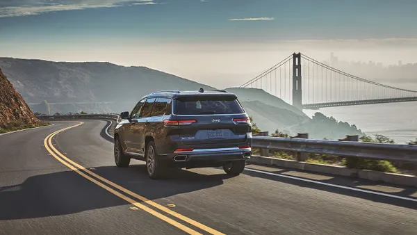 The back of a 2021 Jeep Grand Cherokee L driving on a road with the Golden Gate Bridge in the background.