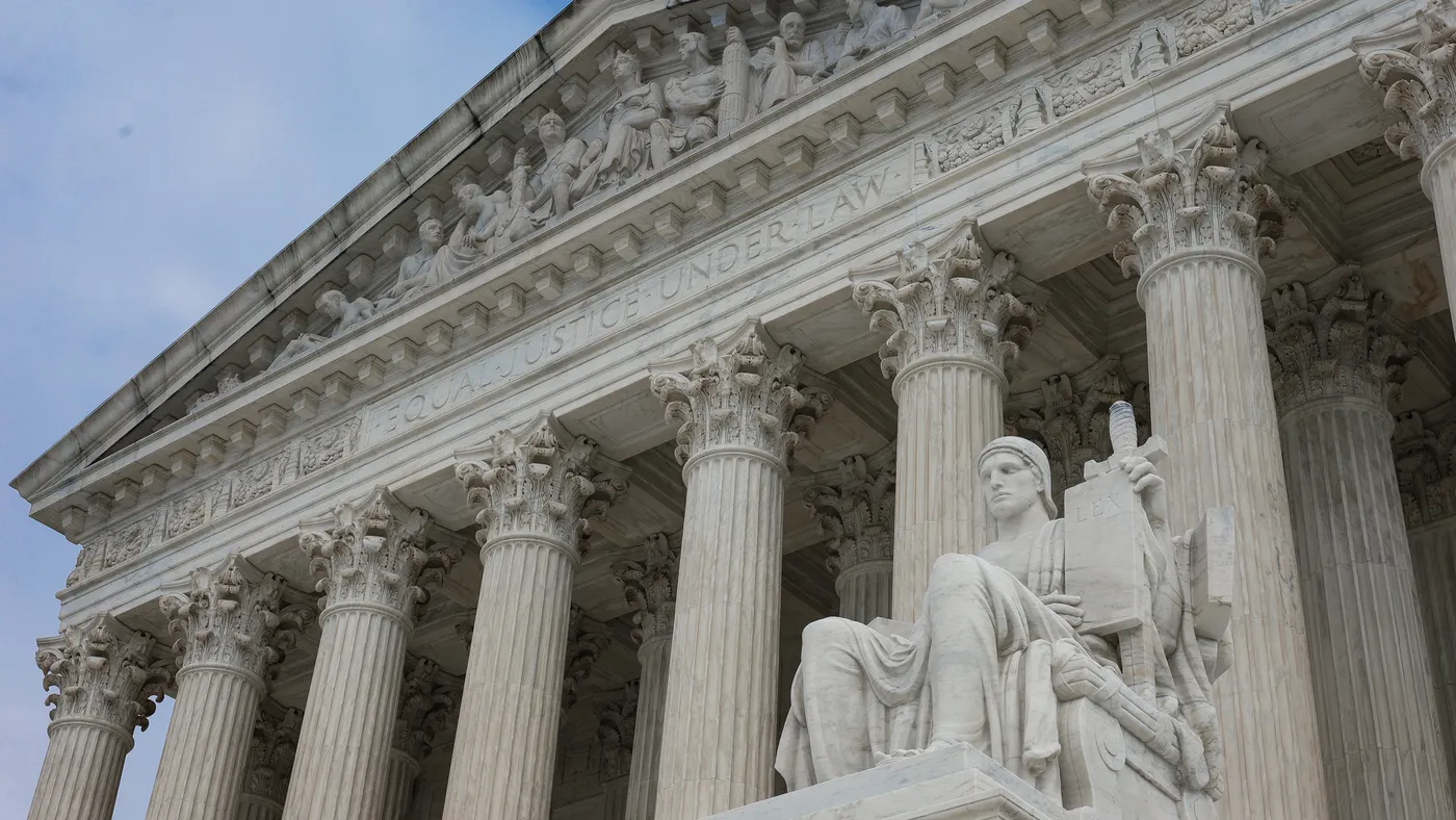 The outside of the U.S. Supreme Court with blue sky and clouds in the background.
