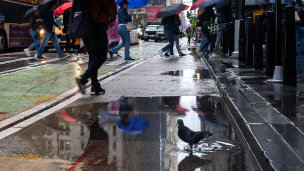 People walk through lower Manhattan during heavy rain and high winds