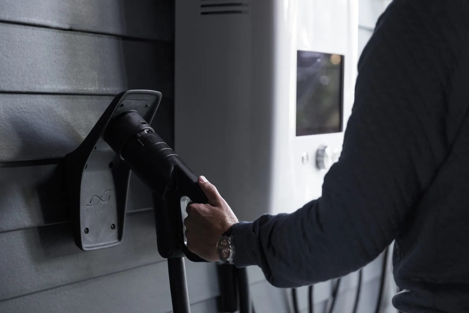 A person hangs an EV charger on a wall.