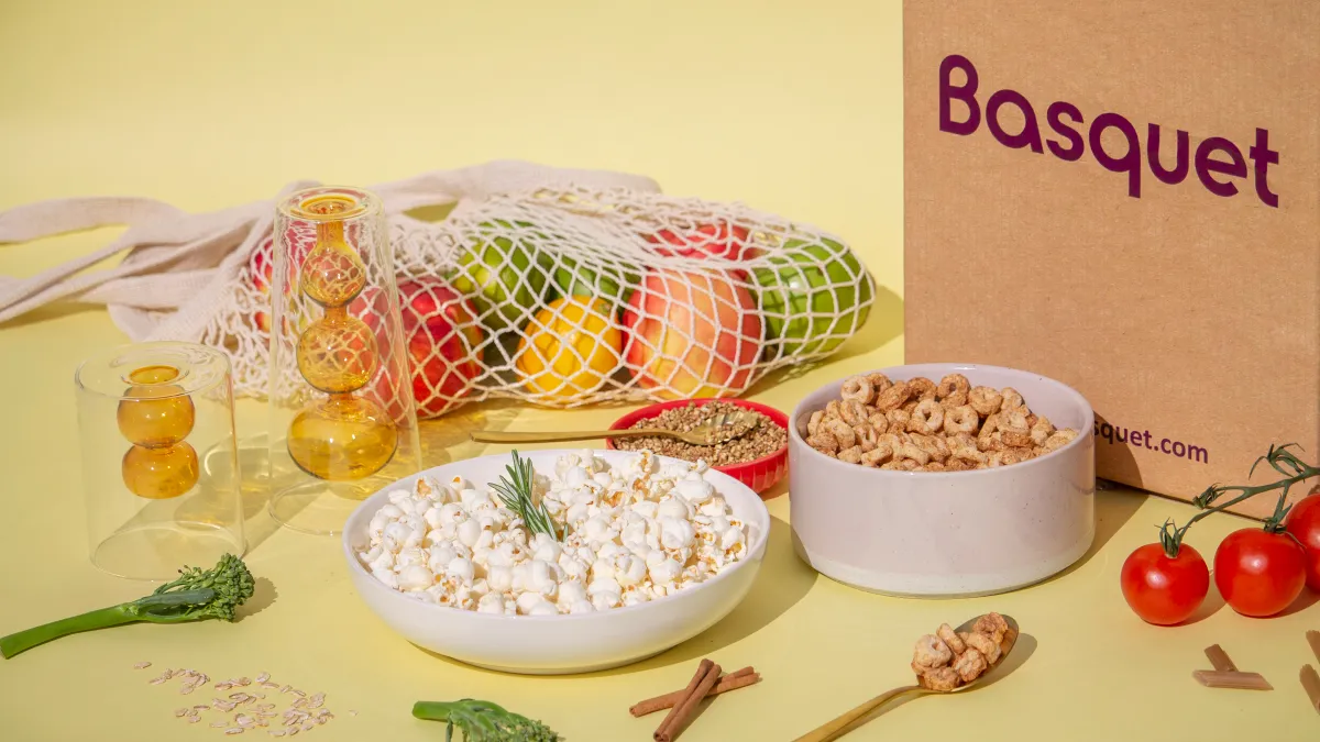 Snack foods and produce on a yellow backdrop with a brown box in the corner