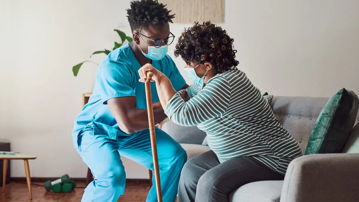 Shot of a young male nurse helping an elderly patient stand.