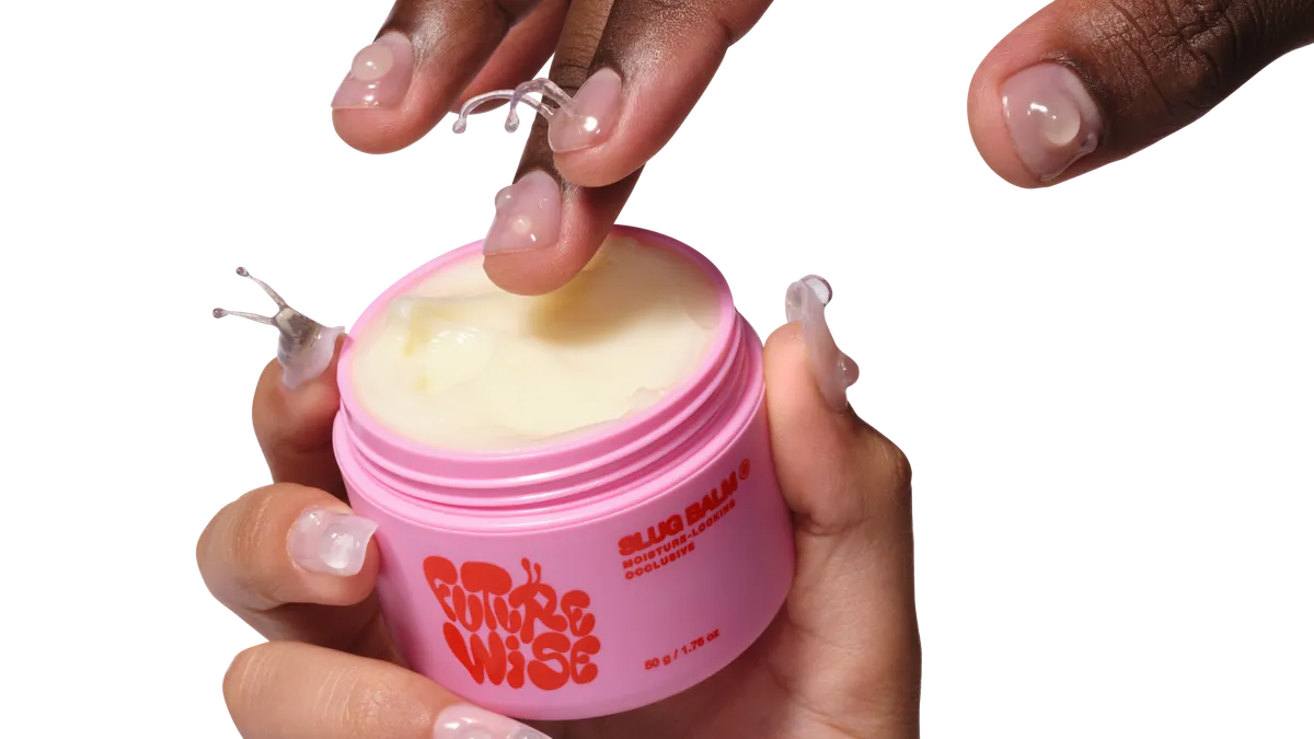 Three hands holding three bright pink and red skincare bottles