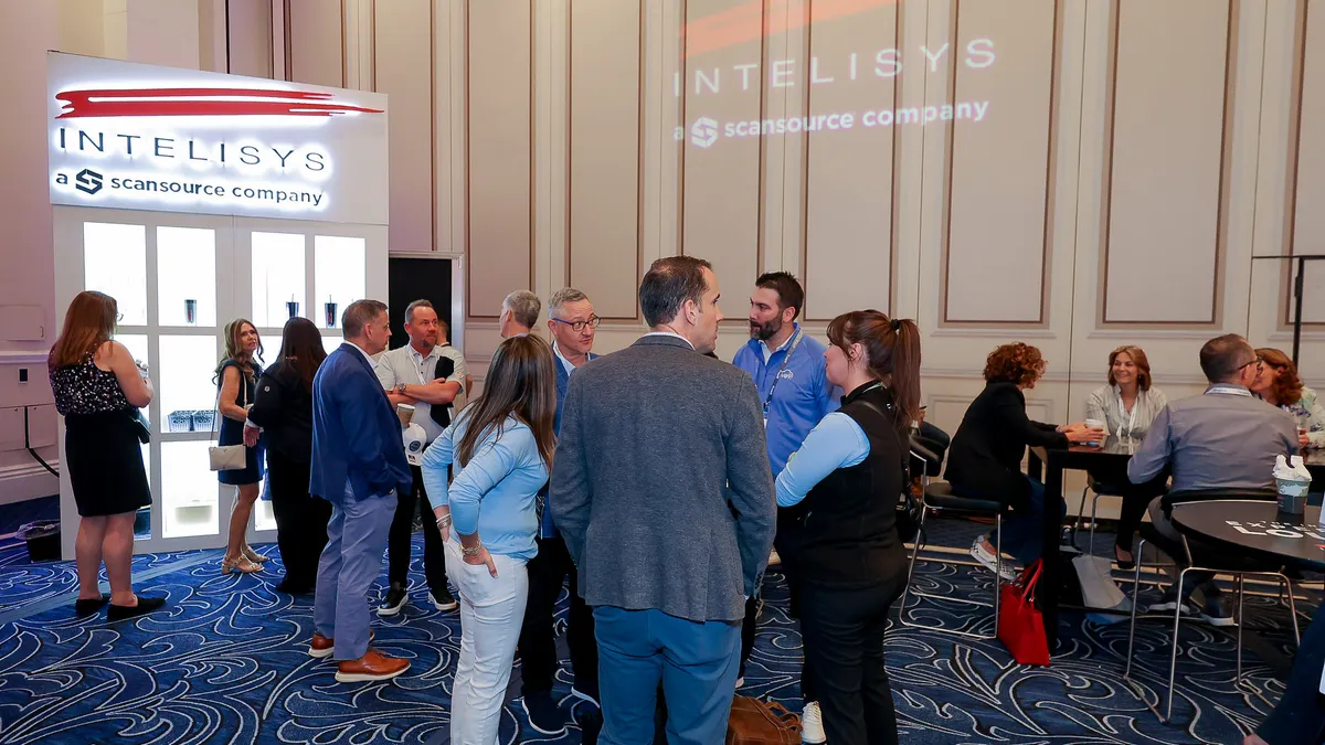 People dressed in business casual attire network in a meeting room titled "Intelisys, a ScanSource company."