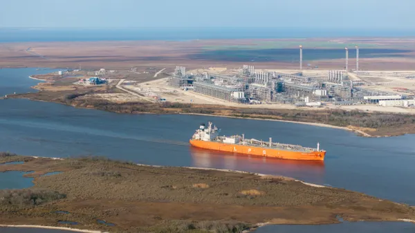 A cargo ship passing by a liquefied natural gas plant.