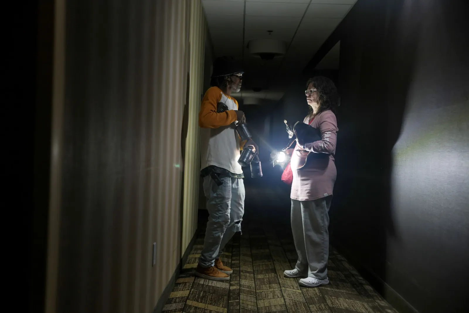 two people with flashlights in a dark hallway
