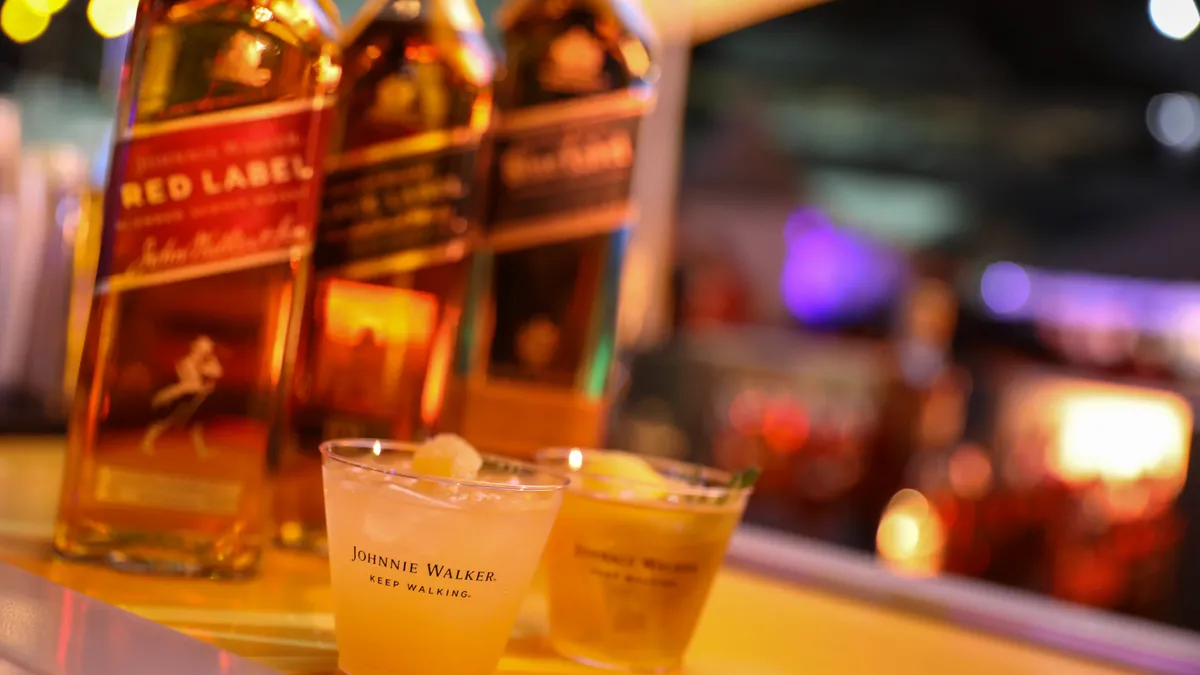 Bottles of Johnnie Walker next to plastic cups filled with a cocktail.