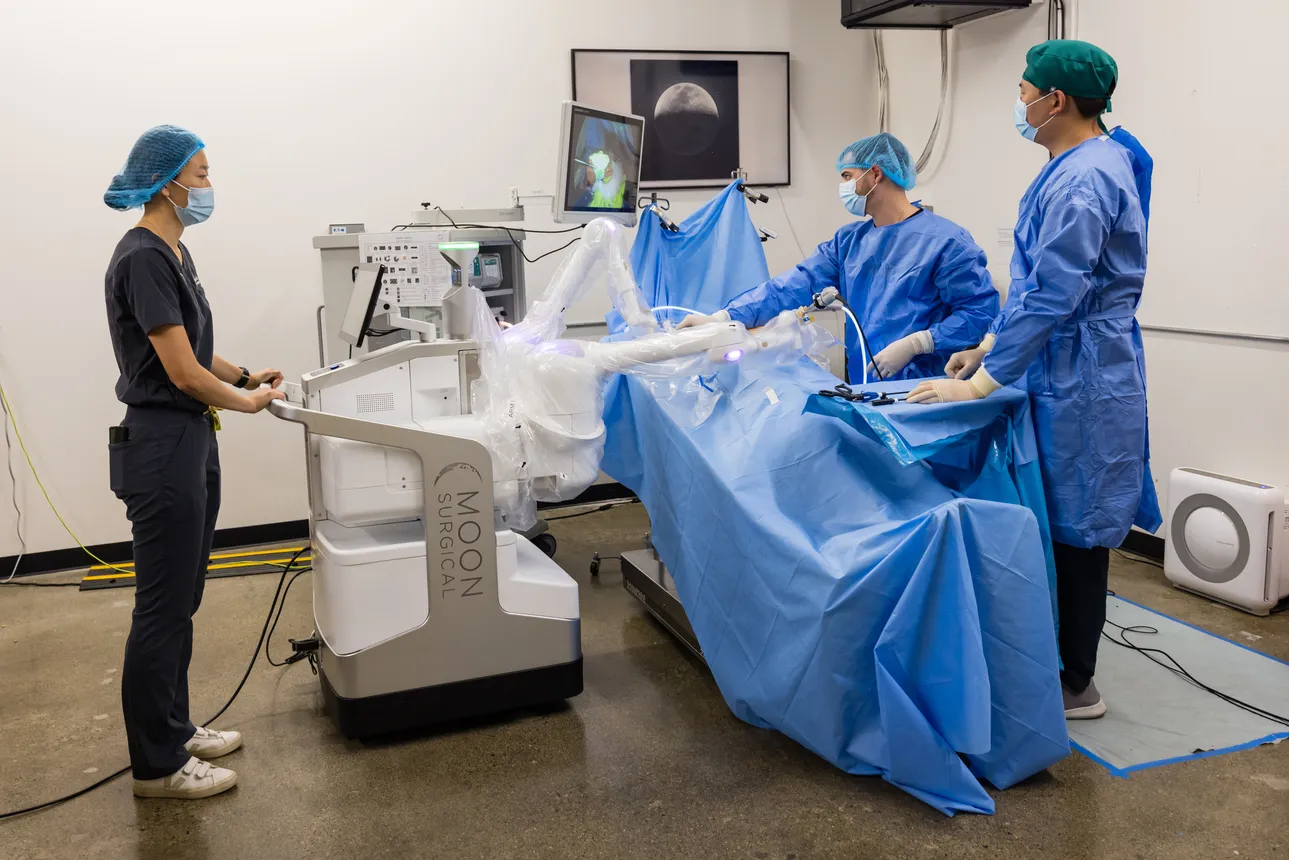 Moon Surgical's Maestro robot is displayed in an operating room, accompanied by three clinicians.